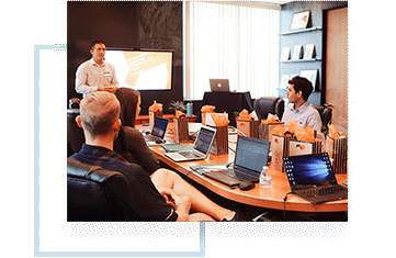 Man teaching a group of professionals with computers, similar to what Blue Sky Business Consulting does
